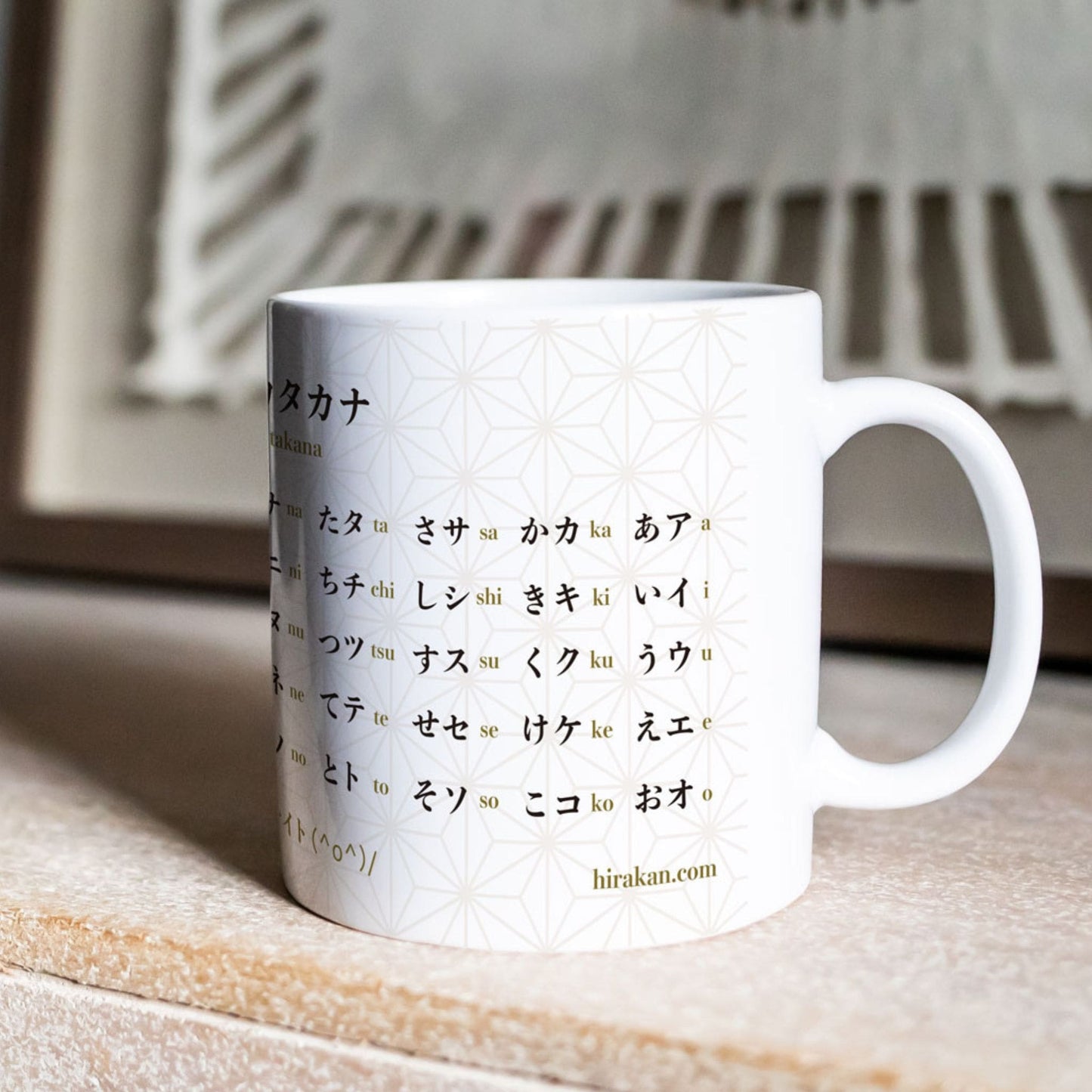 Mug with hiragana and katakana chart print to learn Japanese language on a desk