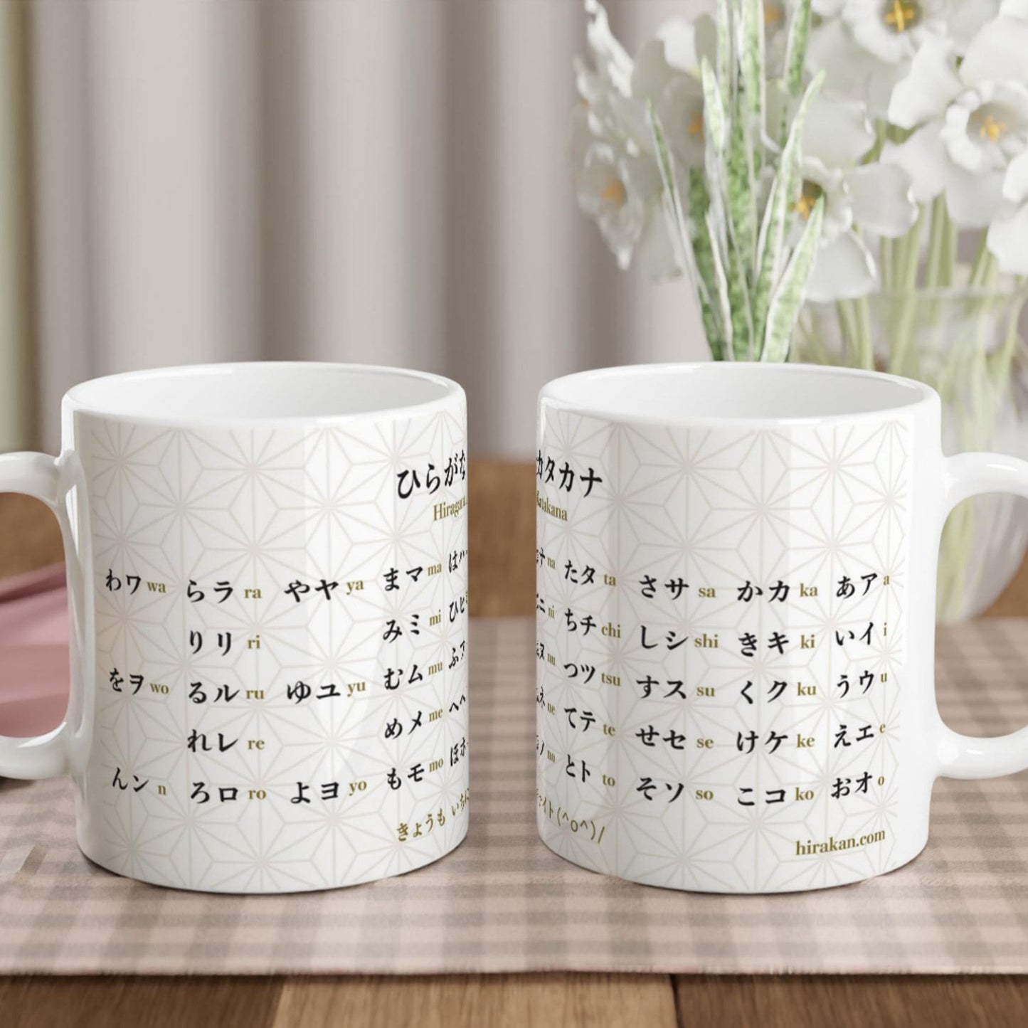 2 mugs with hiragana and katakana chart print to learn Japanese language facing each other on a table