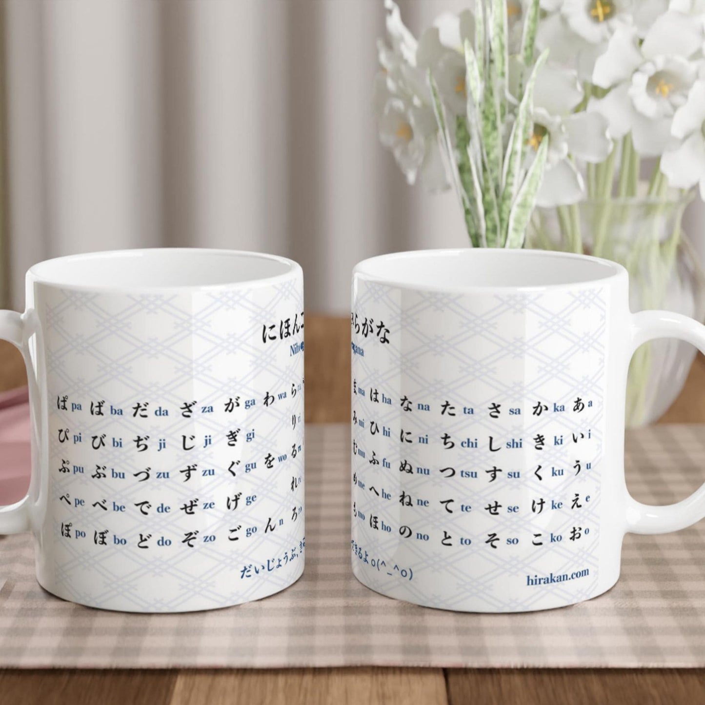 Two mugs with hiragana chart print for Japanese language learning facing each other on a table